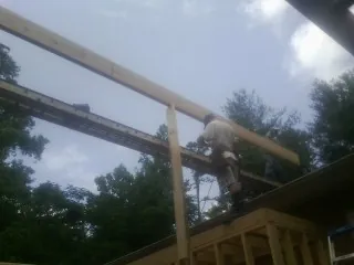 Carpenter setting a ridge beam over a new addition frame — Ice Dam Removal by Roofing Brothers in Bloomfield Hills