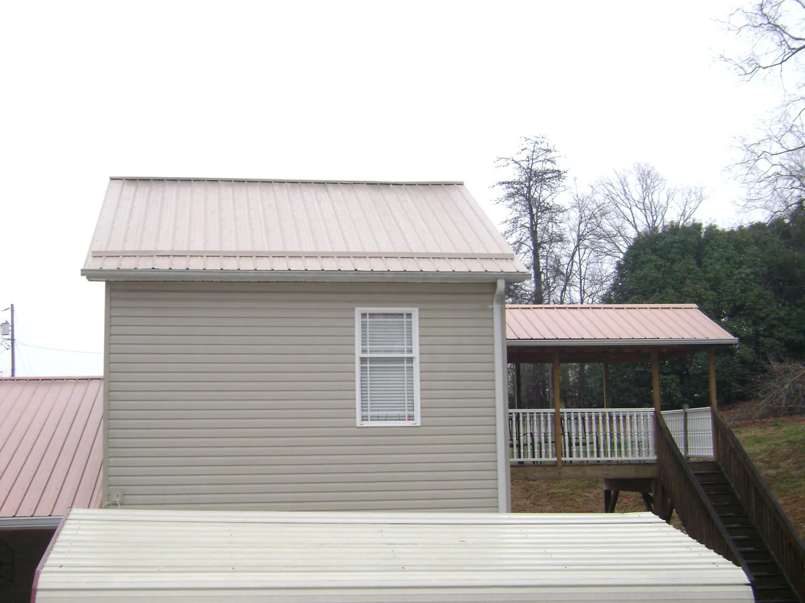 Tan metal roofs on a two story addition and attached porch, from a Roof Replacement job in Bloomfield Hills