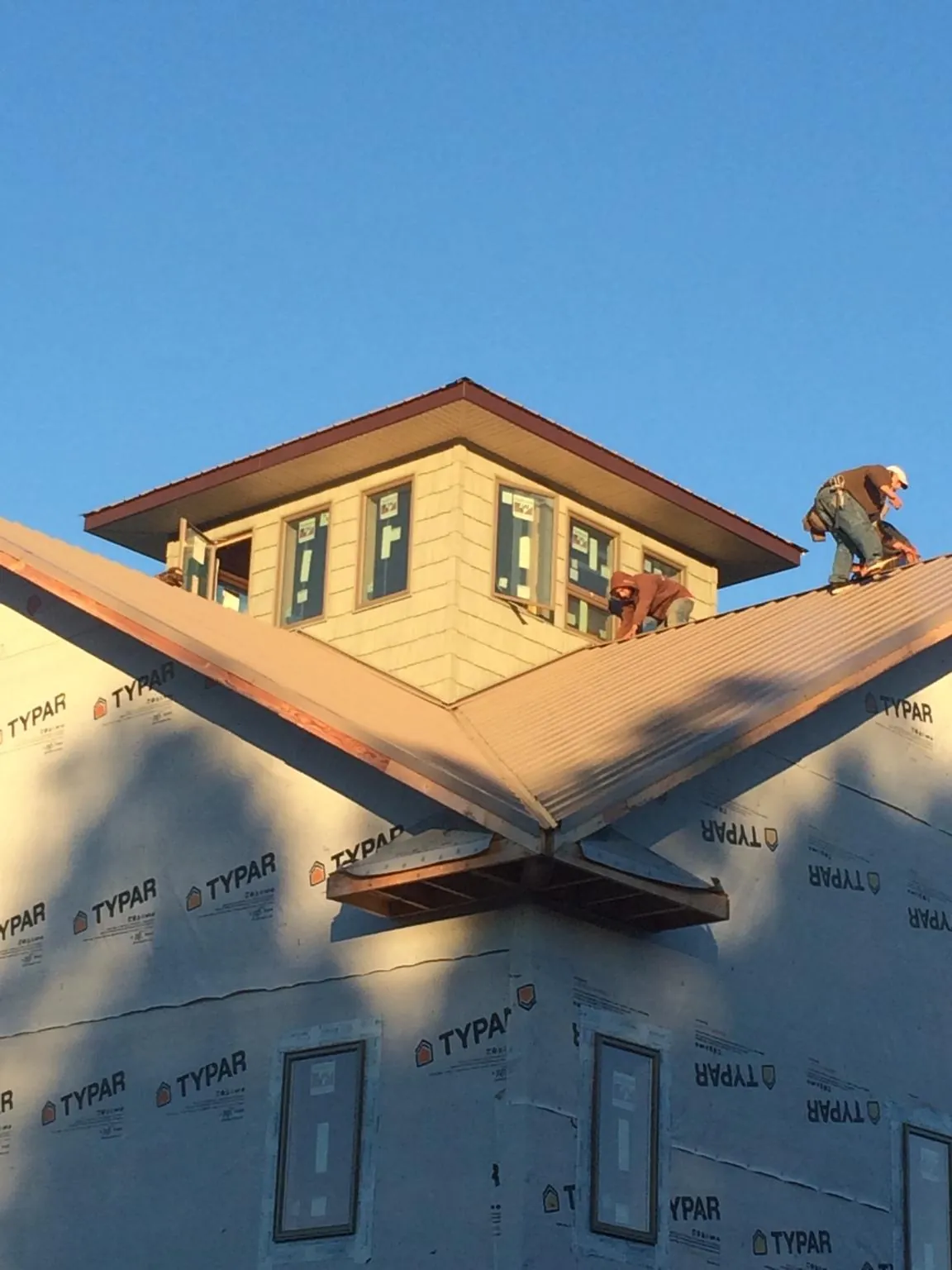 Roofers working around a rooftop cupola on a new metal roof at sunset — Roof Waterproofing in Bloomfield Hills by Roofing Brothers